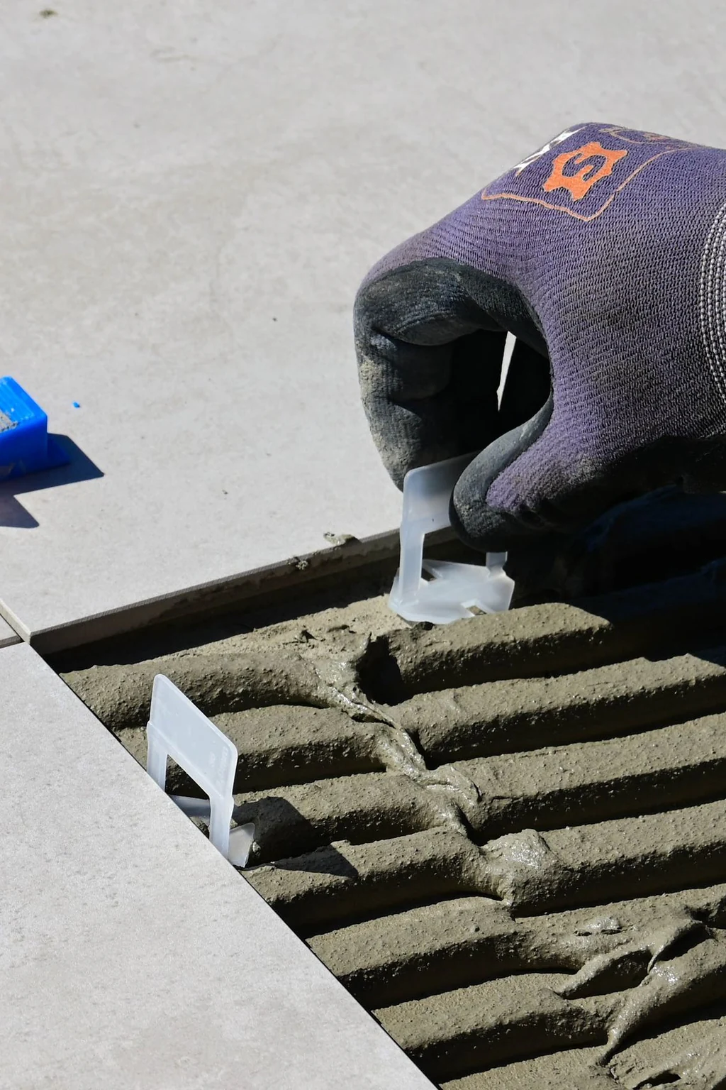 Installer setting large-format porcelain tile with a leveling system