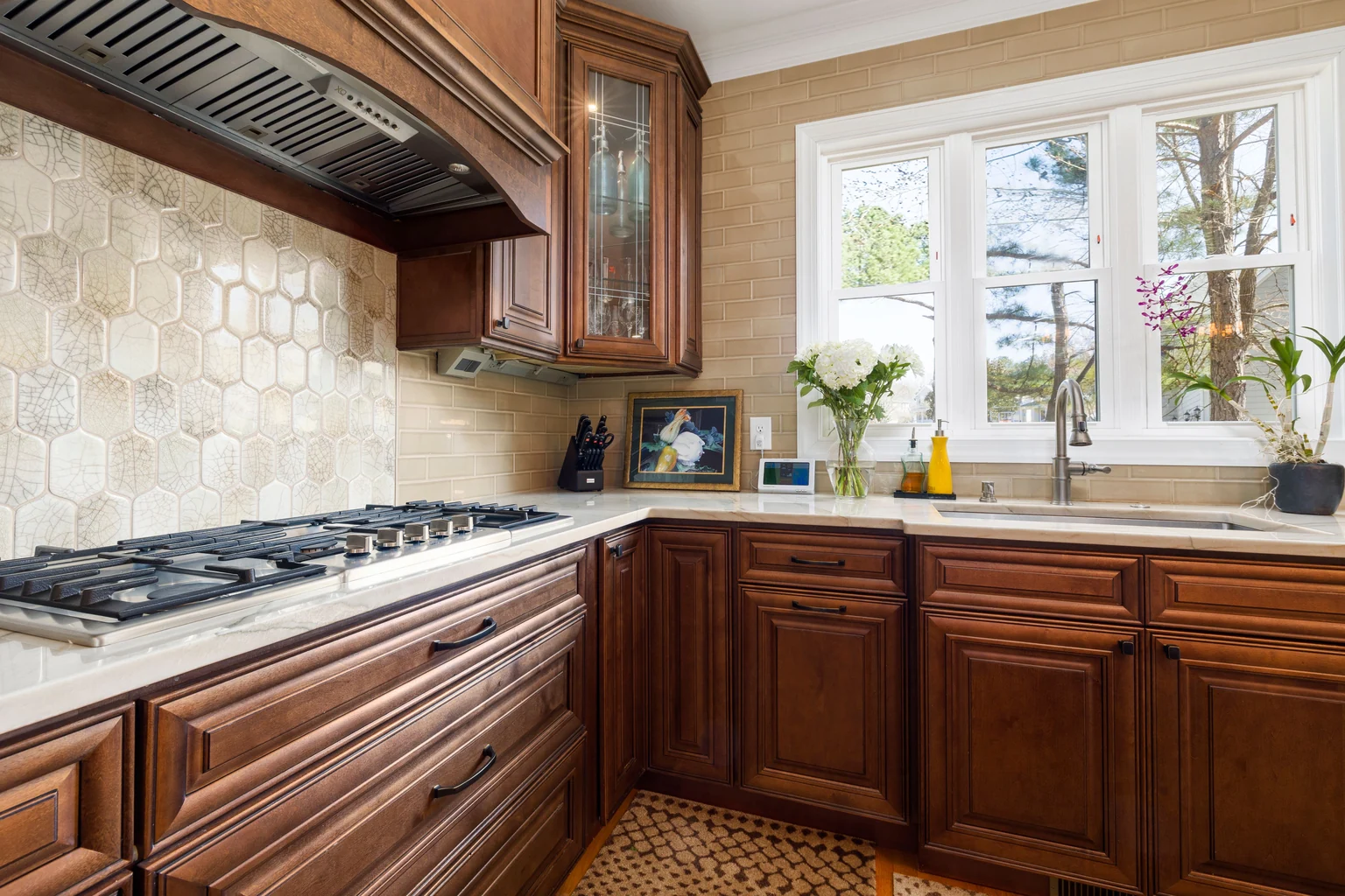 Hexagon tile backsplash behind a gas range with wood cabinets