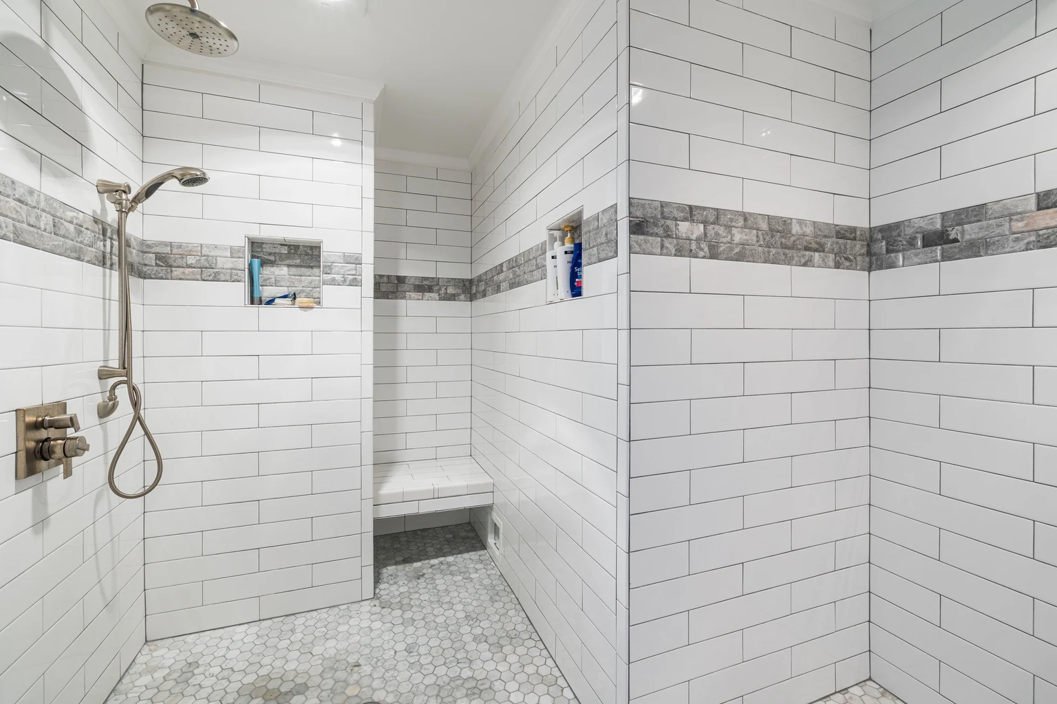 White subway tile shower with a recessed niche and a built-in bench